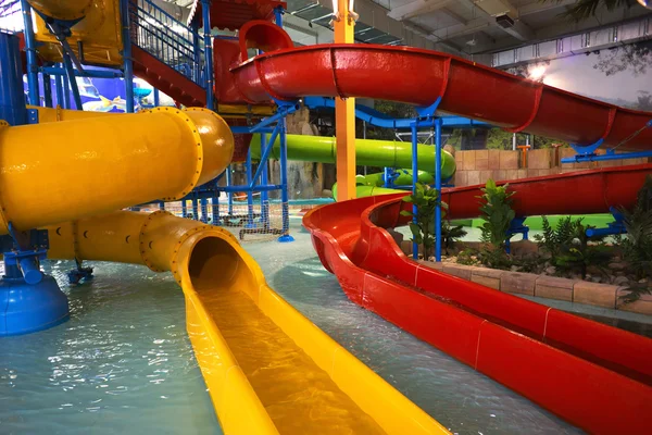 Bright red and yellow water slides in an indoor water park setting.